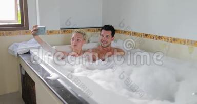 年轻夫妇在手机上自拍，一起泡澡，男人和女人情人享受水疗